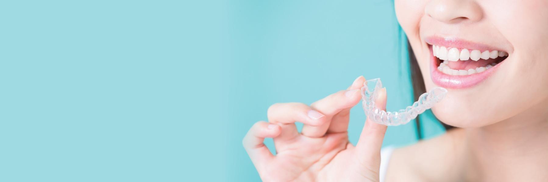 Woman holding tray of Invisalign clear braces in Norfolk MA
