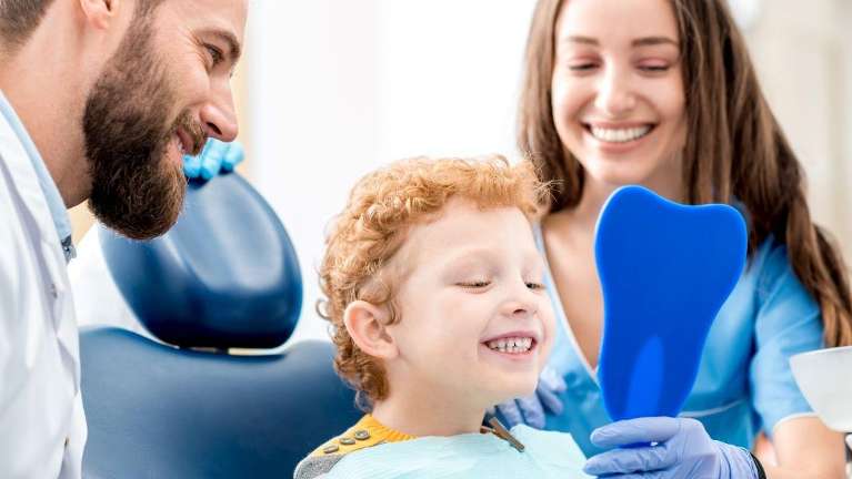 The dental staff showing a young child his smile in the mirror