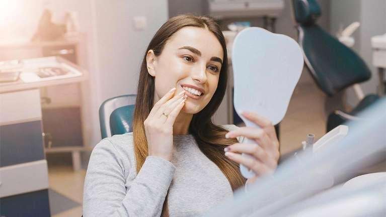 girl looking at the mirror smiling while at the dentist medfield