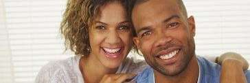 A couple standing close to each other, both wearing big smiles on their faces