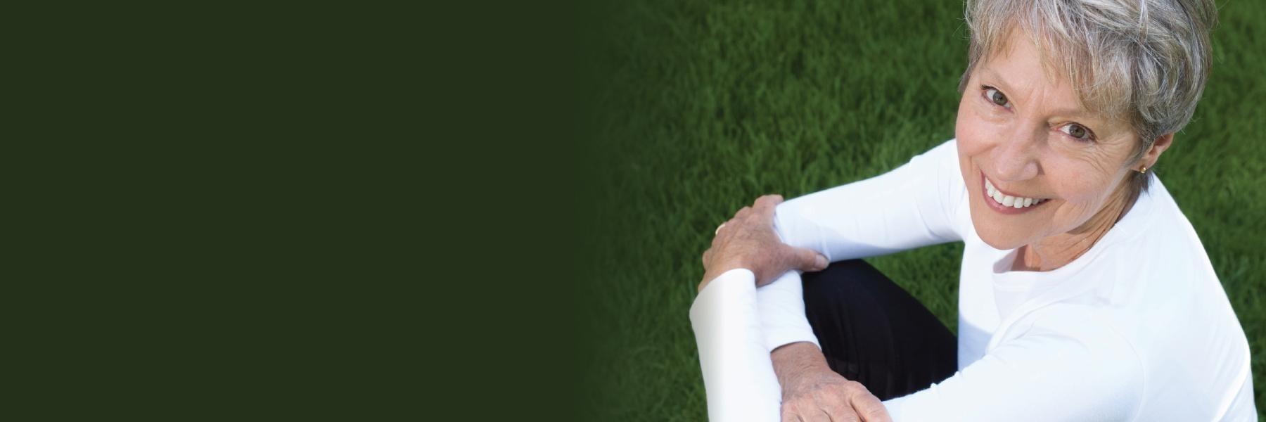 Woman with CEREC dental crowns sitting in the grass near Norfolk MA