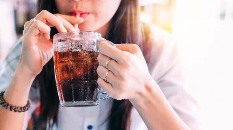 Woman drinking a dark soda at restaurant in Norfolk MA