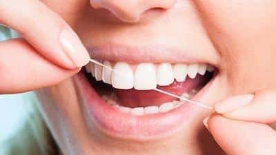 Close up of dental patient flossing their teeth