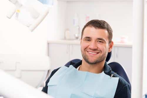 Patient smiling in treatment chair for dental extraction in Norfolk MA